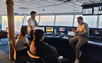 Group of people in front of a ship bridge